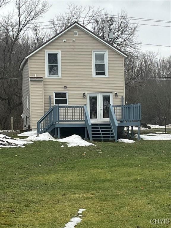 snow covered back of property with a deck and a lawn