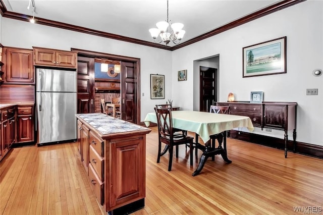 dining area with light hardwood / wood-style floors, crown molding, and a notable chandelier