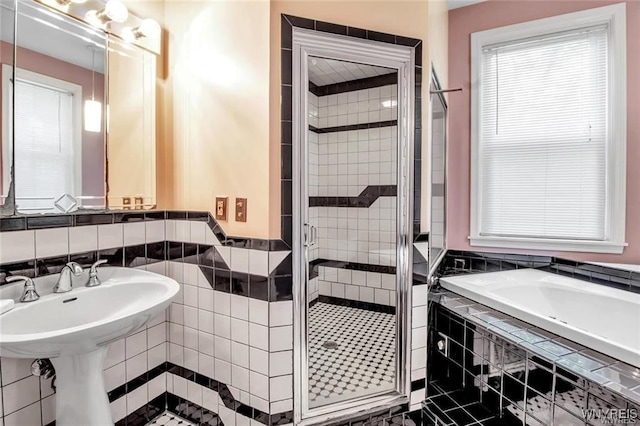 bathroom with tile walls, independent shower and bath, and sink