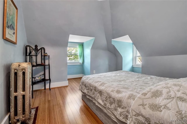 bedroom featuring multiple windows, hardwood / wood-style floors, and vaulted ceiling