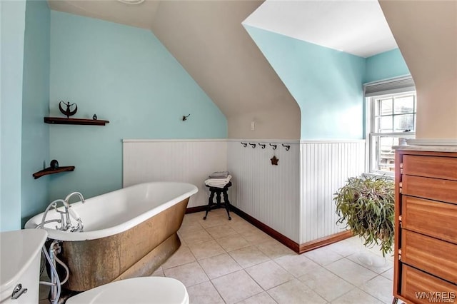 bathroom featuring a bathing tub, vanity, lofted ceiling, and tile patterned flooring