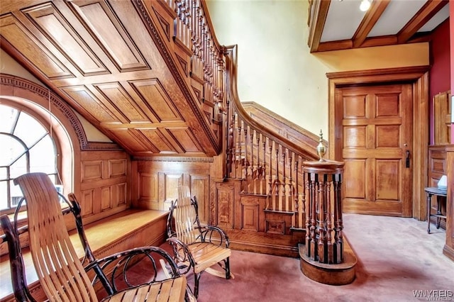 sitting room with beamed ceiling, light colored carpet, coffered ceiling, and wood walls