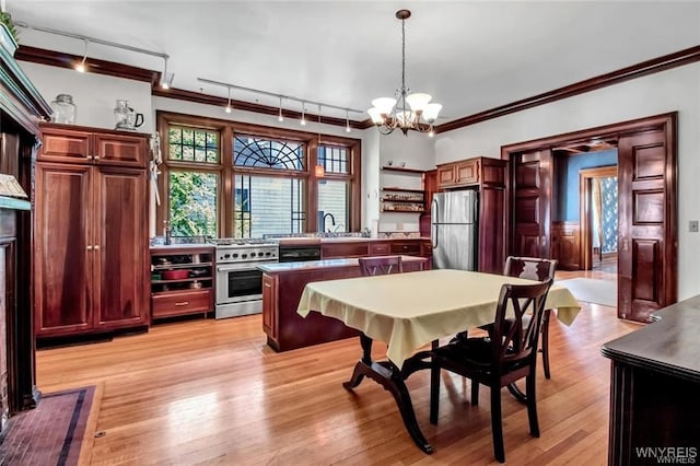 kitchen with stainless steel appliances, sink, light hardwood / wood-style flooring, a notable chandelier, and hanging light fixtures