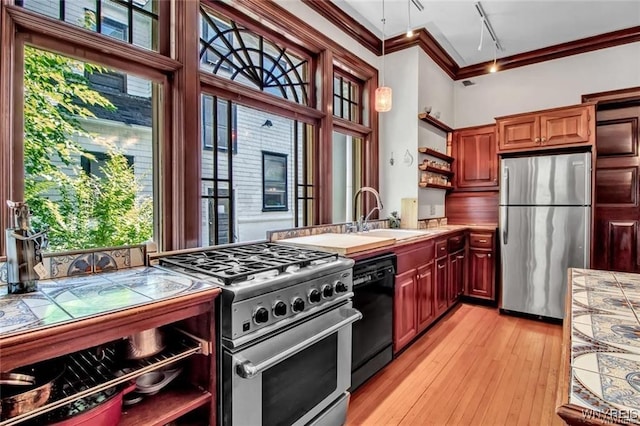 kitchen with stainless steel appliances, crown molding, sink, tile countertops, and light hardwood / wood-style floors