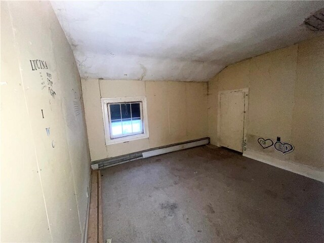 spare room featuring lofted ceiling, concrete floors, and a baseboard heating unit