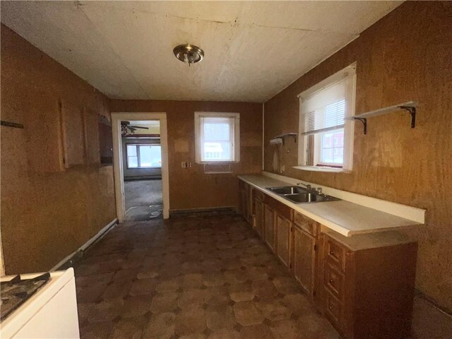 kitchen with ceiling fan, sink, and wooden walls