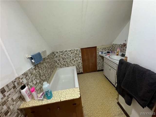 bathroom with vanity, lofted ceiling, and a bath