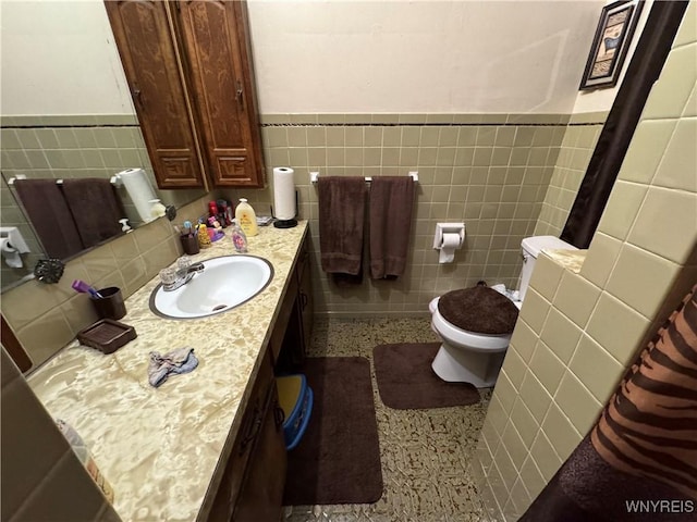 bathroom with vanity, tile walls, and toilet