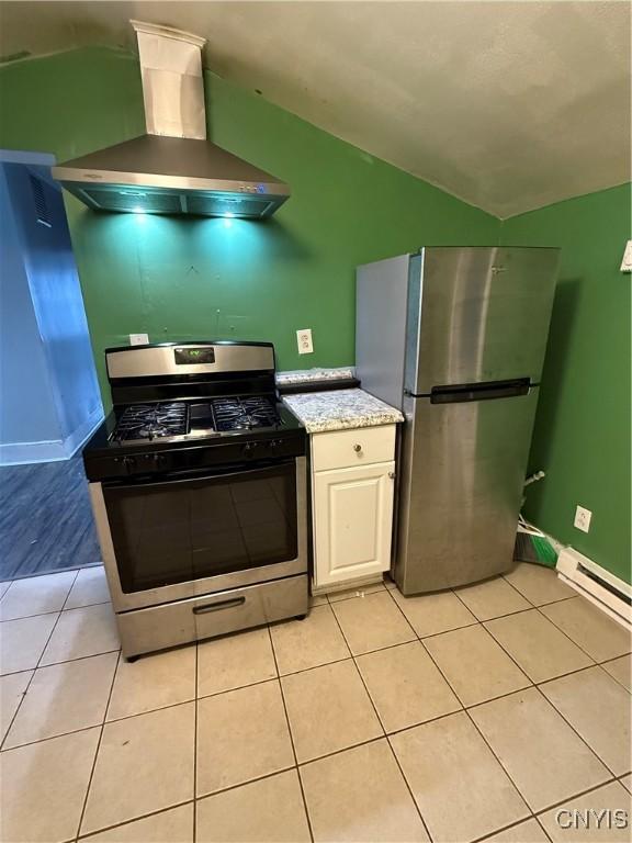 kitchen featuring light tile patterned floors, a baseboard heating unit, white cabinets, exhaust hood, and appliances with stainless steel finishes