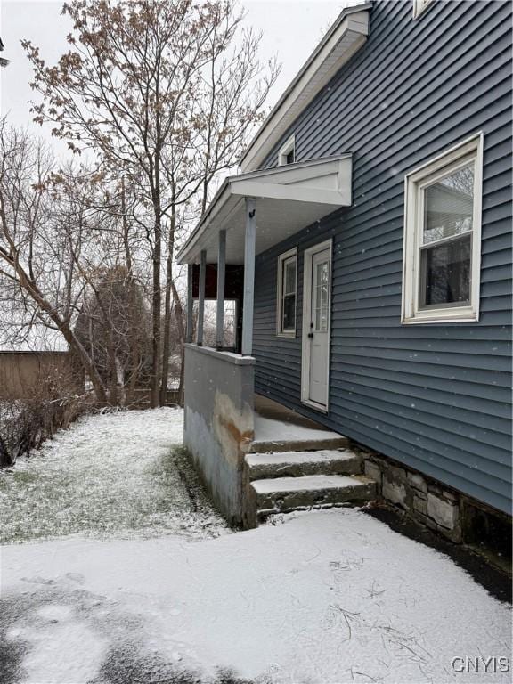 snow covered property entrance with a porch