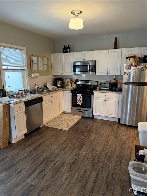 kitchen with dark wood-type flooring, sink, decorative backsplash, white cabinetry, and stainless steel appliances