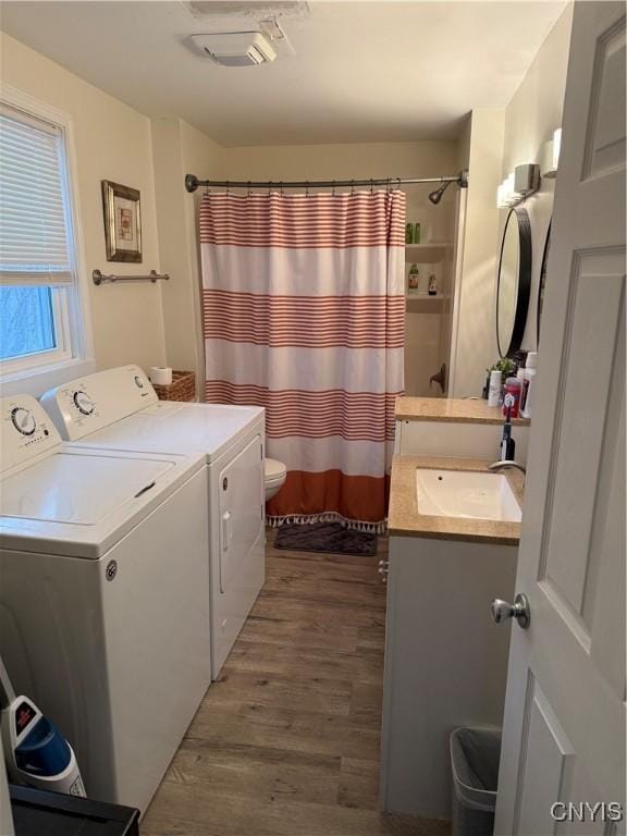 clothes washing area with dark hardwood / wood-style flooring, washing machine and dryer, and sink