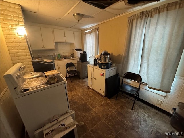 kitchen with white cabinets, a paneled ceiling, and washer / clothes dryer