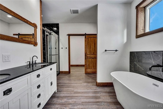 bathroom with wood-type flooring, vanity, and shower with separate bathtub