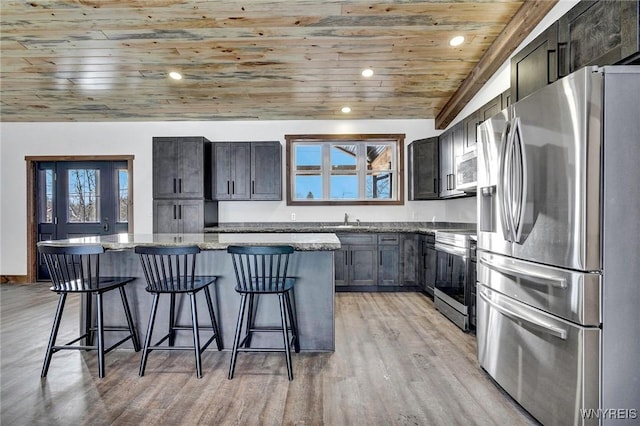 kitchen with stone counters, a center island, wooden ceiling, a kitchen bar, and appliances with stainless steel finishes