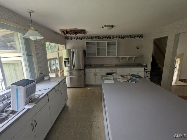 kitchen with white cabinets, decorative light fixtures, stainless steel fridge, and tasteful backsplash