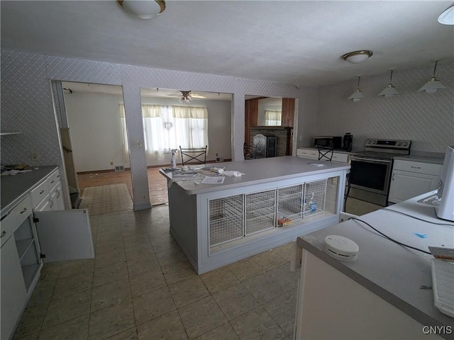 kitchen featuring white cabinets, ceiling fan, a kitchen island, and electric stove