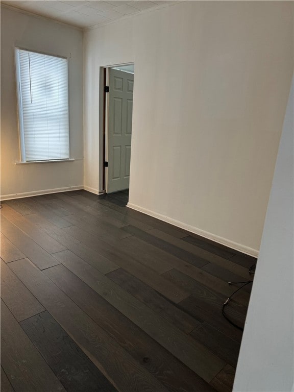 empty room with baseboards and dark wood-style flooring