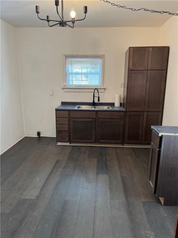kitchen featuring dark brown cabinets, dark wood-style floors, a chandelier, and a sink