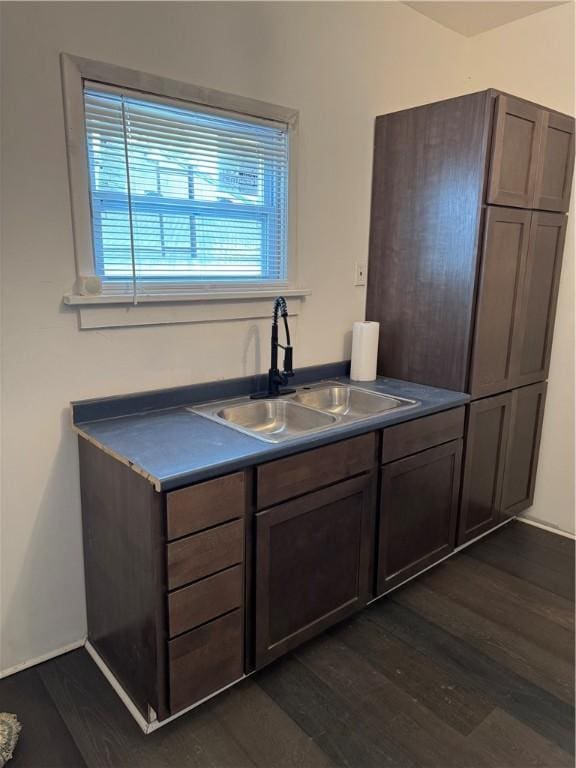 kitchen featuring dark wood finished floors, dark countertops, and a sink