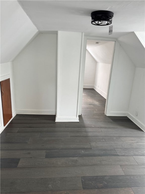 bonus room with baseboards, dark wood finished floors, and vaulted ceiling