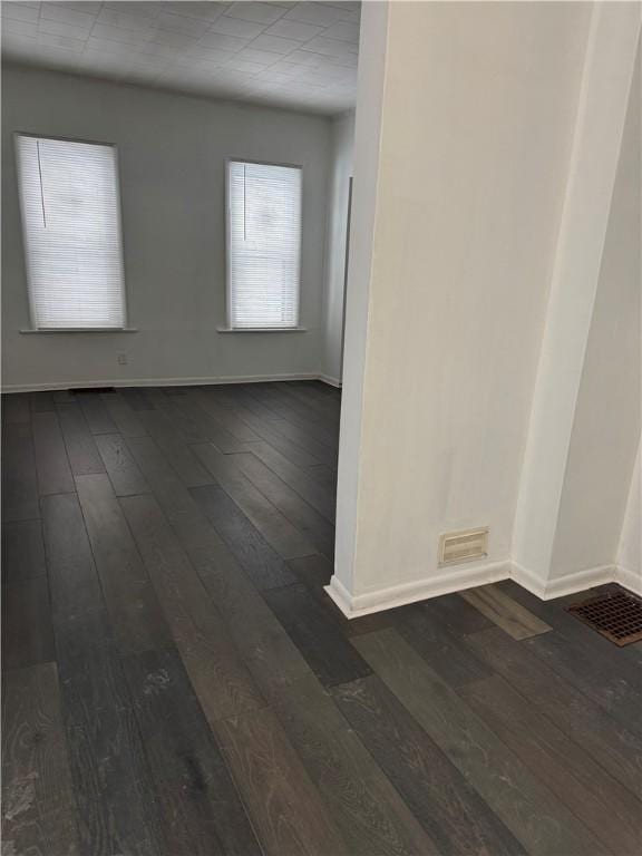 spare room featuring dark wood-style floors, visible vents, and baseboards