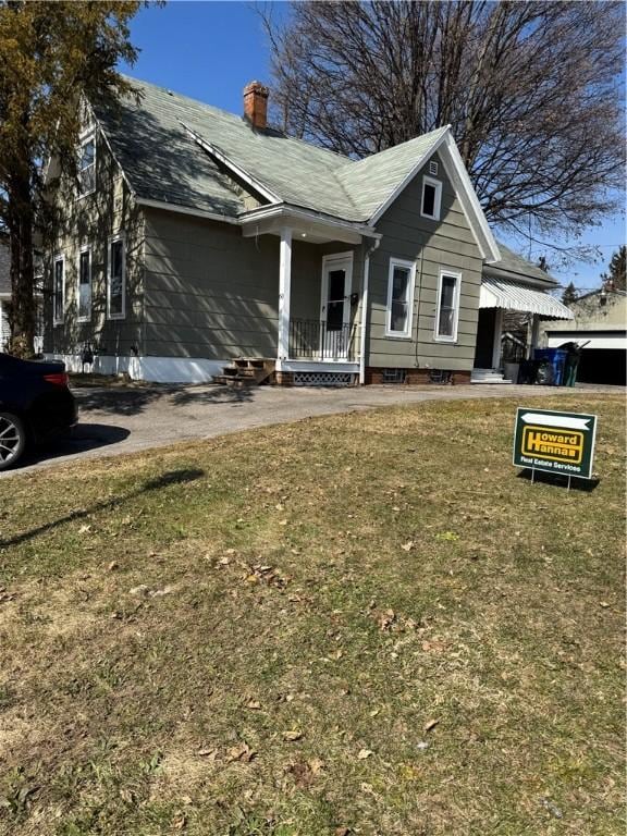 view of front of property with a porch, a chimney, and a front yard