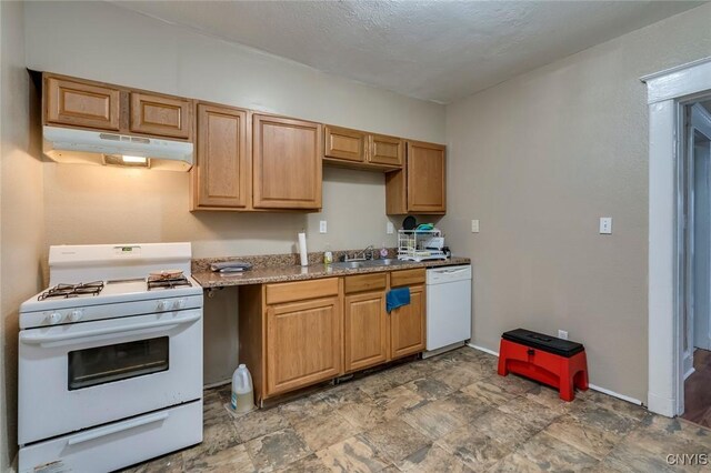 kitchen featuring light stone countertops, white appliances, and sink