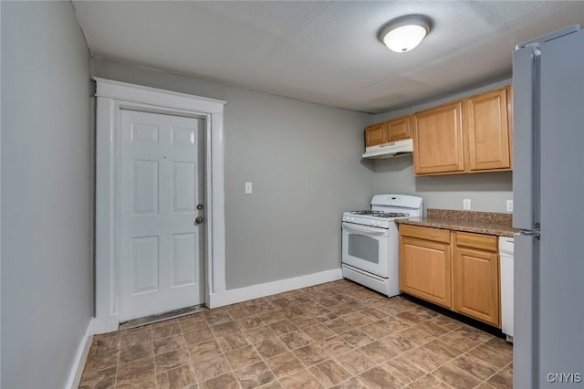 kitchen featuring light brown cabinets, white appliances, and a textured ceiling