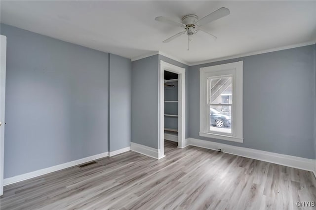 unfurnished bedroom featuring ceiling fan, ornamental molding, light hardwood / wood-style flooring, and a closet