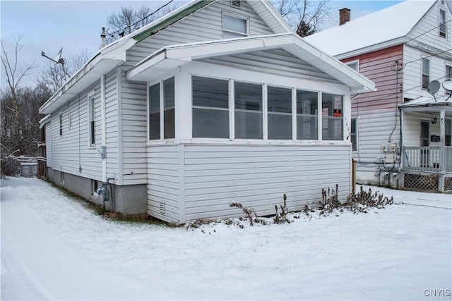 view of snow covered exterior with a sunroom