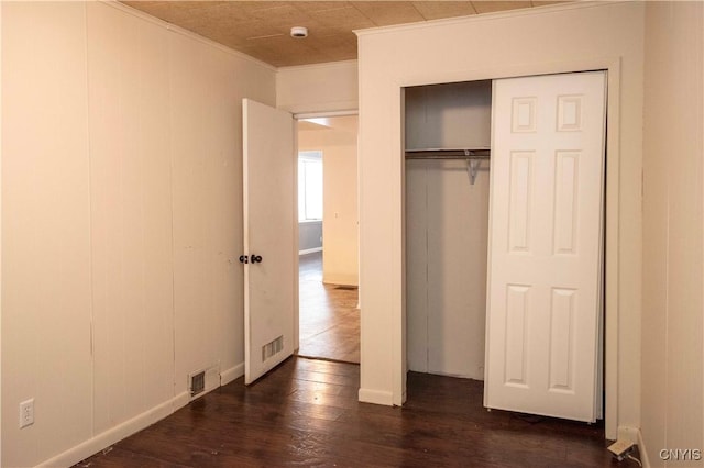 unfurnished bedroom featuring dark hardwood / wood-style floors, a closet, and ornamental molding