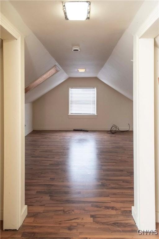 additional living space featuring dark wood-type flooring and lofted ceiling