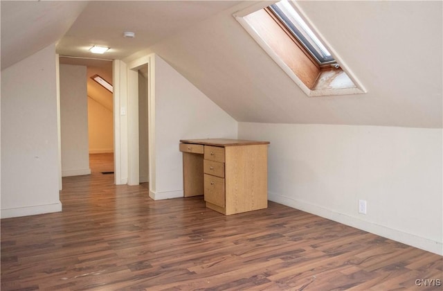 additional living space featuring vaulted ceiling with skylight and dark hardwood / wood-style floors