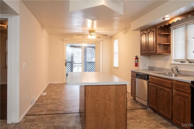 kitchen featuring decorative backsplash, stainless steel dishwasher, ceiling fan, sink, and a kitchen island