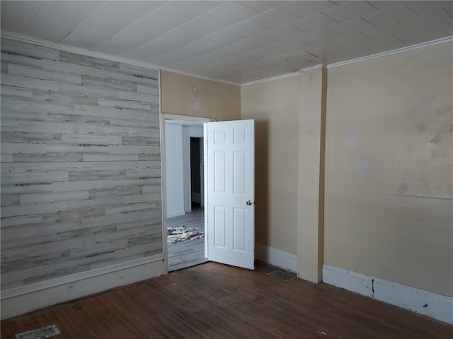 spare room with wooden walls, ornamental molding, and dark hardwood / wood-style flooring