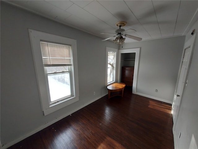 empty room featuring dark hardwood / wood-style flooring, plenty of natural light, and ceiling fan