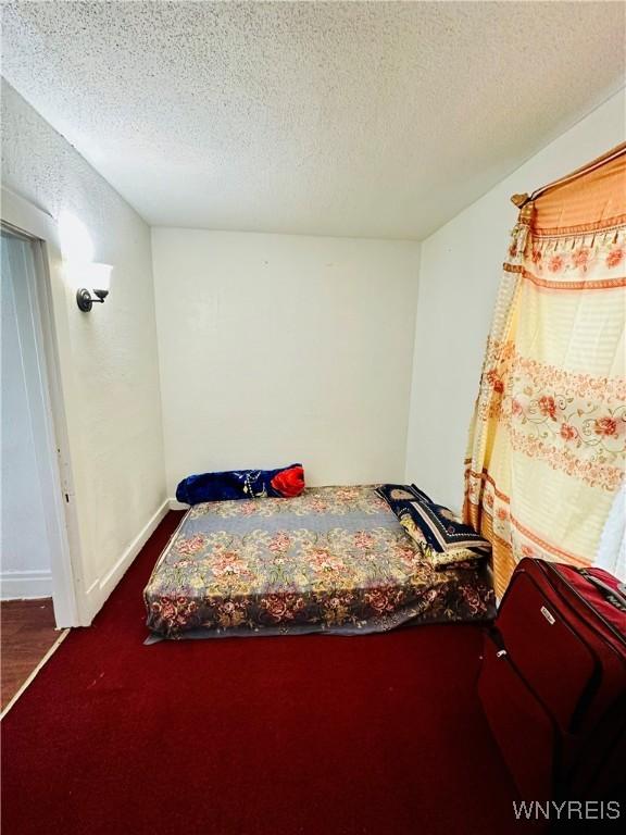 bedroom featuring a textured ceiling and dark colored carpet