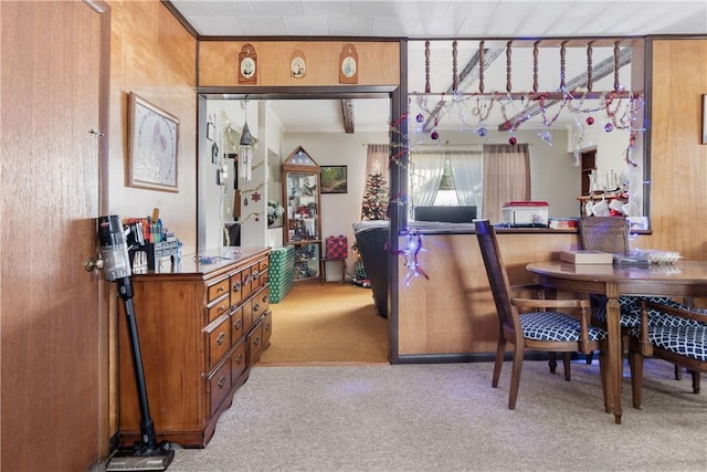 carpeted dining area featuring wood walls