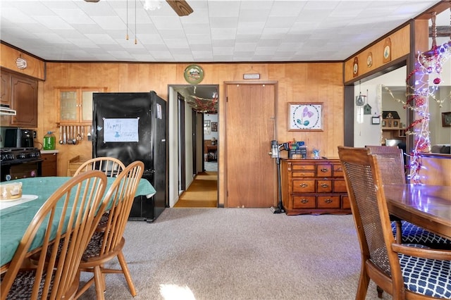 carpeted dining space featuring wooden walls and ornamental molding