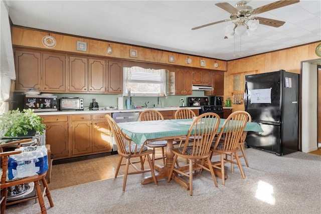 kitchen featuring wood walls, black appliances, ceiling fan, ornamental molding, and light colored carpet