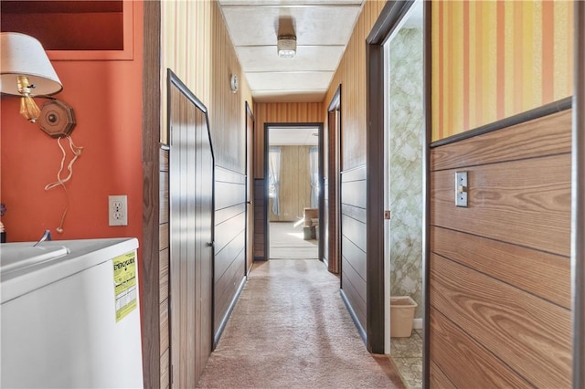 hall featuring wood walls and light colored carpet