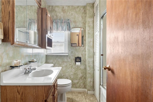 full bathroom featuring toilet, vanity, tile patterned floors, and bath / shower combo with glass door