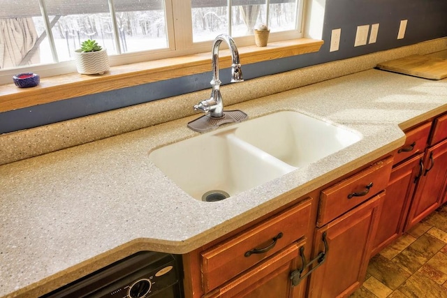 kitchen featuring light stone counters, sink, and dishwasher