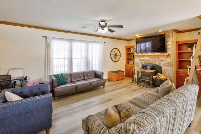 living room with ornamental molding, a wood stove, ceiling fan, and light hardwood / wood-style flooring