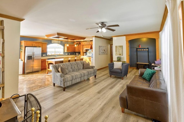 living room with ornamental molding, ceiling fan, and light wood-type flooring