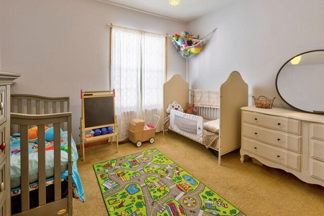 bedroom with light carpet and a crib