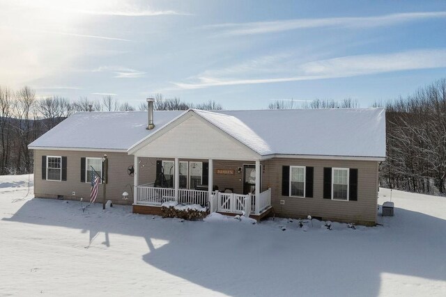 snow covered back of property featuring a porch