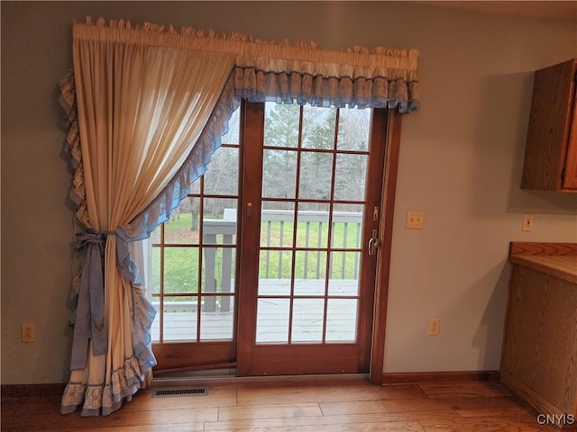 entryway with light wood-style flooring, visible vents, and baseboards