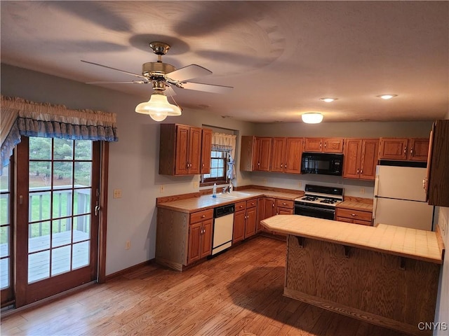 kitchen with white appliances, sink, ceiling fan, tile counters, and light hardwood / wood-style floors